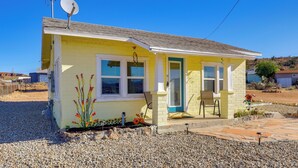 A small yellow house with a satellite dish, a door, and a chair outside. - Route 66 Roadtripper Retreat w/ Private Backyard (Kingman)