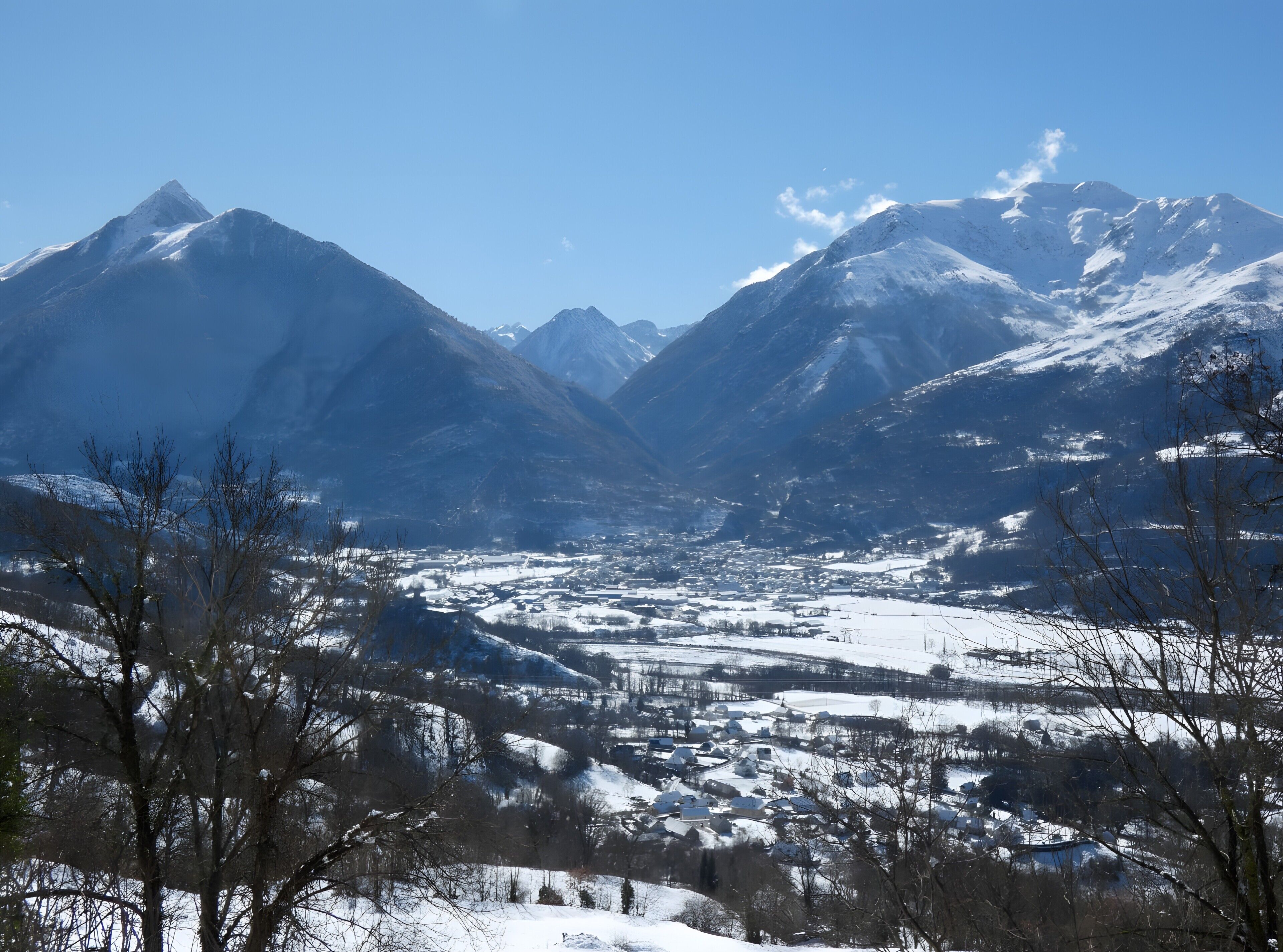 Un paysage montagneux, avec des sommets enneigés et une vallée en contrebas.