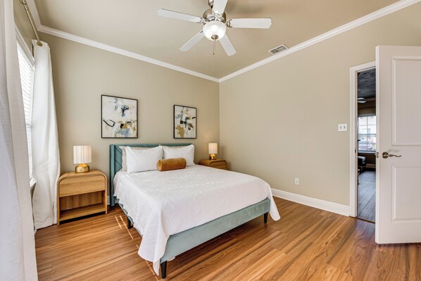 A bedroom with a bed, two bedside tables, a ceiling fan, and artwork on the walls. - 3 Mi to FSU! Townhome w/ Pool Access (Tallahassee)