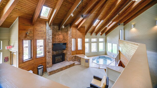 Une pièce spacieuse avec une cheminée en pierre, une piscine et des poutres en bois au plafond.