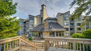 Un immeuble à plusieurs étages doté d’une tour centrale, de balcons et d’une terrasse en bois.