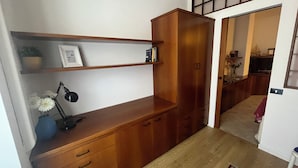 Ein Holztisch mit Schubladen und Regalen, eine Vase mit Blumen und eine Lampe.