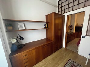 Ein Holztisch mit Schubladen und Regalen, eine Vase mit Blumen und eine Lampe.