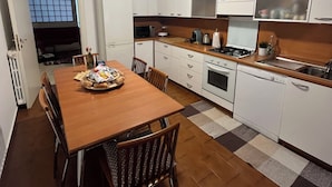 Eine kleine Küche mit weißen Schränken, einem Holztisch und einem eingebauten Backofen.