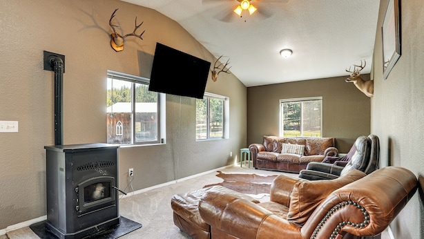 A living room with a fireplace, leather sofa, and deer antlers on the wall. - Peaceful Farm Stay Near Spokane: Inland Hideaway! (Chattaroy)