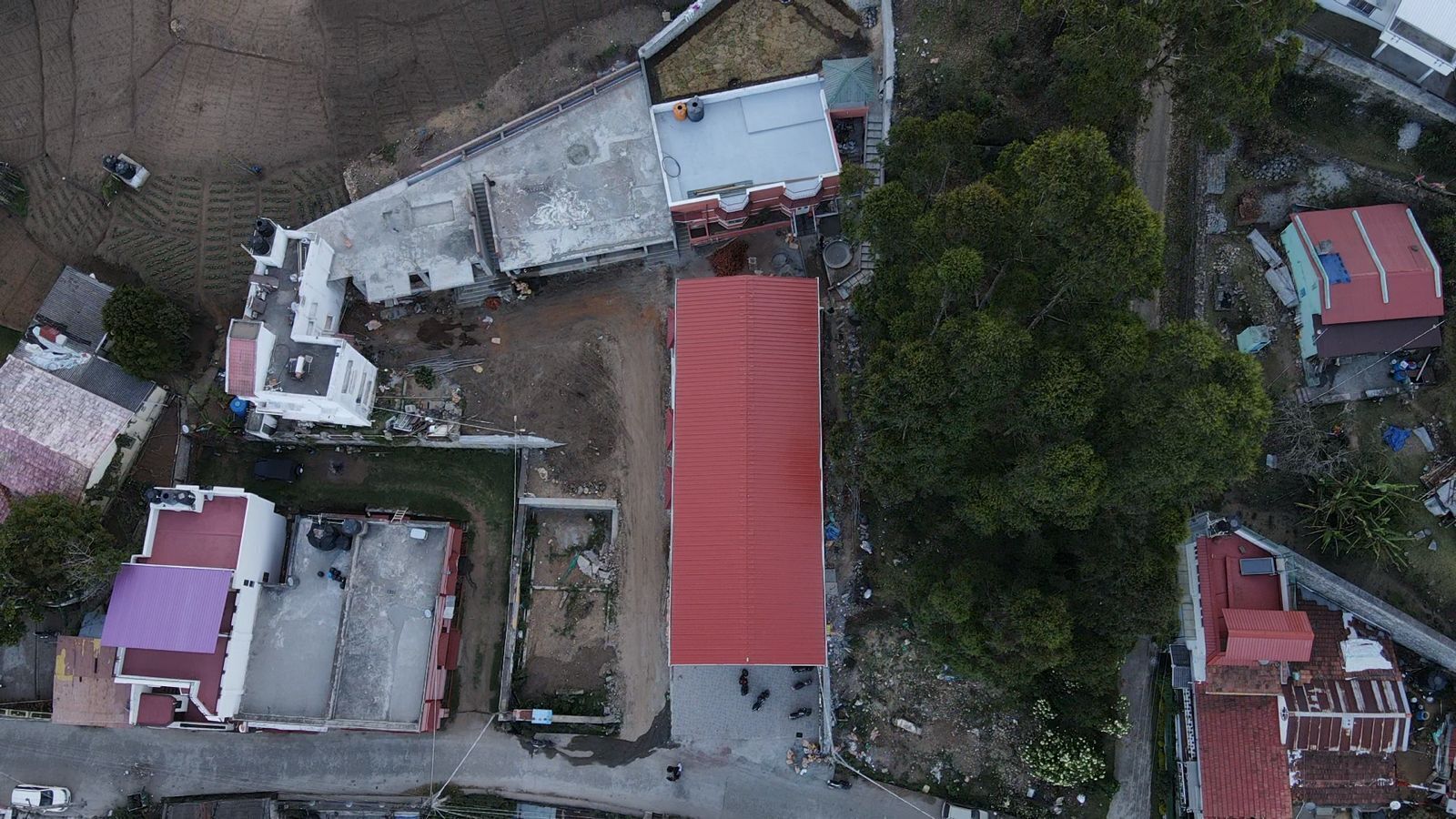 Vista aérea de una zona residencial con varios edificios, incluyendo una construcción destacada con techo rojo.