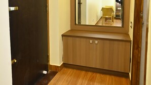 A hallway with a wooden door, a mirror, and a wooden bench. - KULIR KODAI INN  (Kodaikanal)