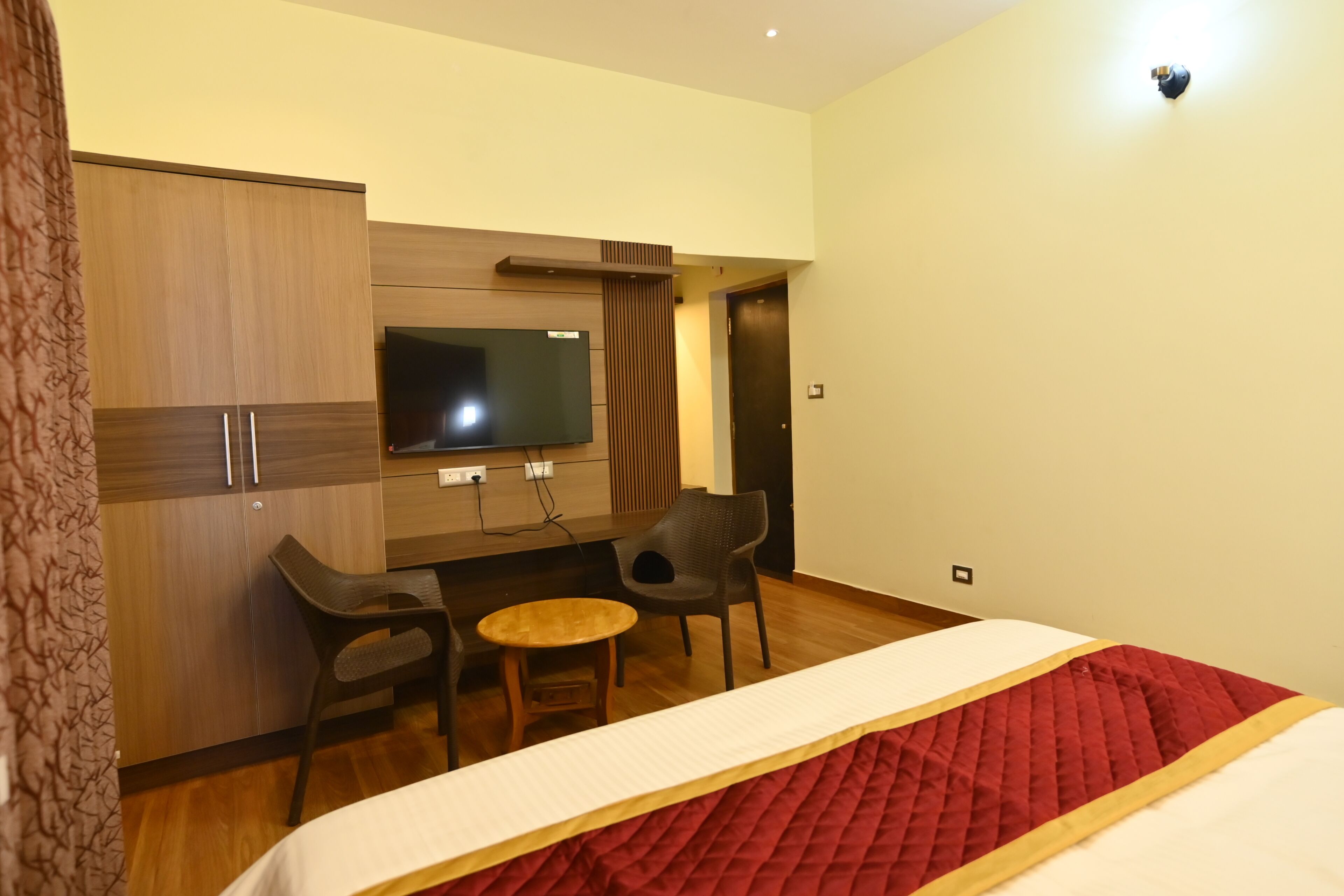 A hotel room with a bed, a desk with two chairs, a television, and a wardrobe.