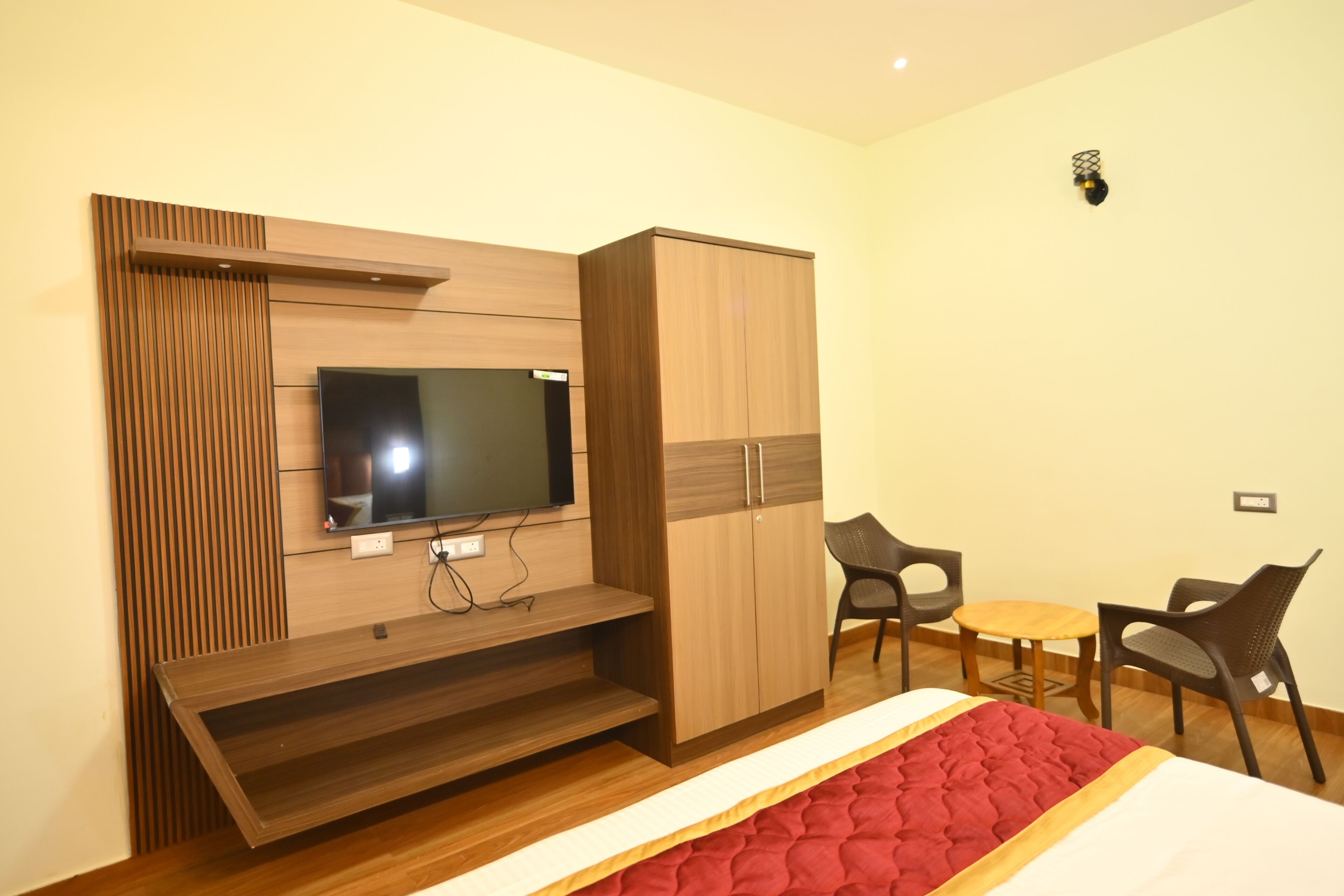 Una habitación de hotel moderna con televisor, muebles de madera, una cama y un pequeño comedor.