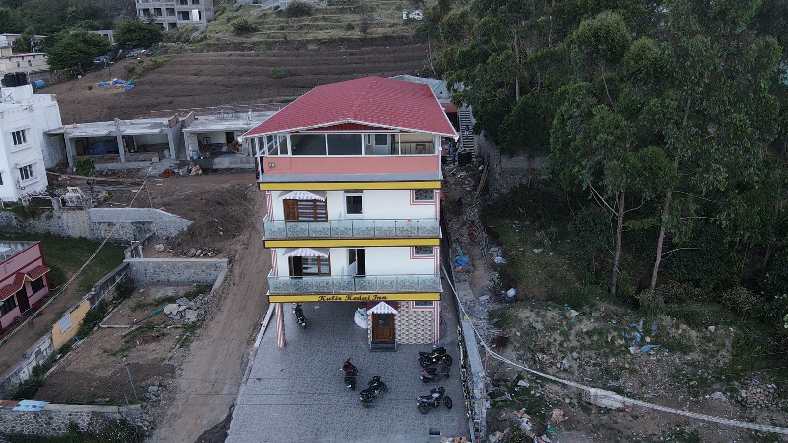 A multi-story building with a red roof, balconies, and a ground-level entrance.