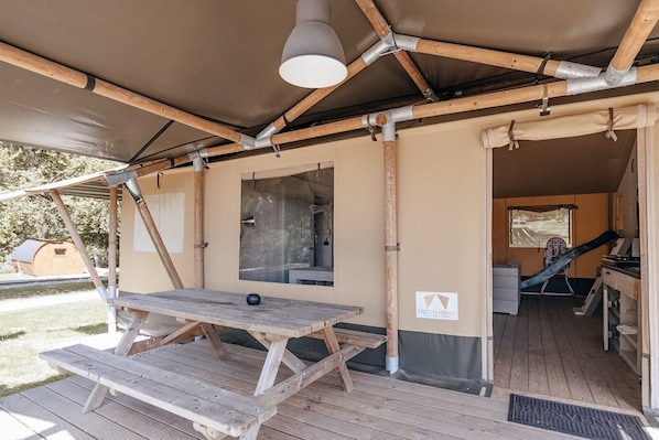 A tented outdoor area with a picnic table, a window, and a slide.