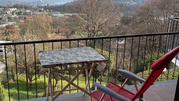 Ein Balkon mit Tisch und Stuhl, der Blick auf eine Stadt und Hügel bietet.
