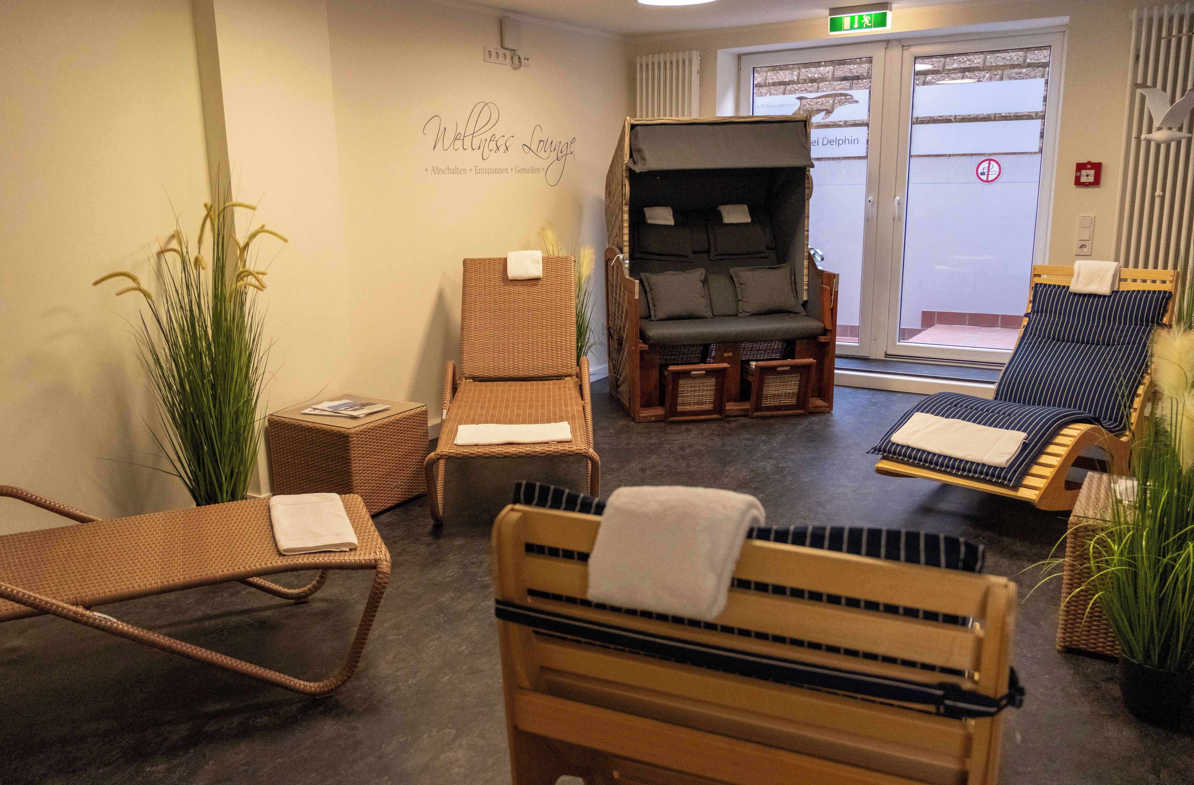 A wellness lounge with wicker furniture, a massage chair, and a view of the outside.