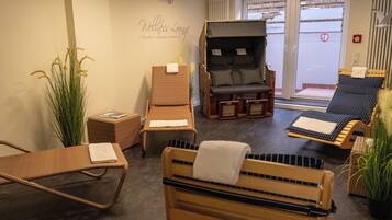 A wellness lounge with wicker furniture, a massage chair, and a view of the outside.