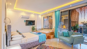 Quarto moderno com cama, banheira, sofá e televisão.