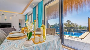 Uma área de refeições com uma mesa posta para dois, uma garrafa de vinho e vista para uma piscina.