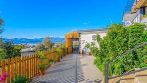 A hotel entrance with a wooden fence, potted plants, and a view of mountains in the background. - Private Villa Sahin-2 Pool Heater Available (Kaş)