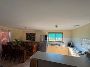 Una cocina compacta con comedor, un refrigerador, una estufa y una ventana con persianas.