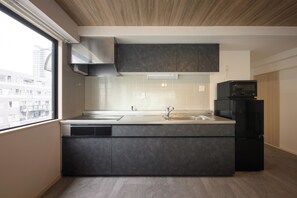 A modern kitchen with a large window, built-in appliances, and a view of the city. - Shinjuku 6-chome City Stay (Tokyo)
