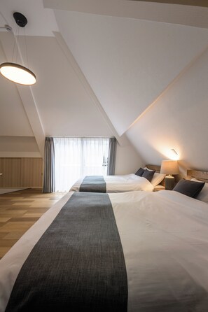 A hotel room with two beds, a ceiling light, a bedside table with a lamp, and a window with curtains. - Shinjuku 6-chome City Stay (Tokyo)