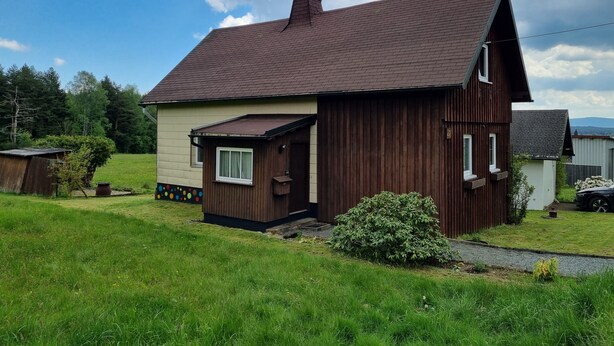 Een gelijkvloers huis met schuin dak, een klein terras en een garage.