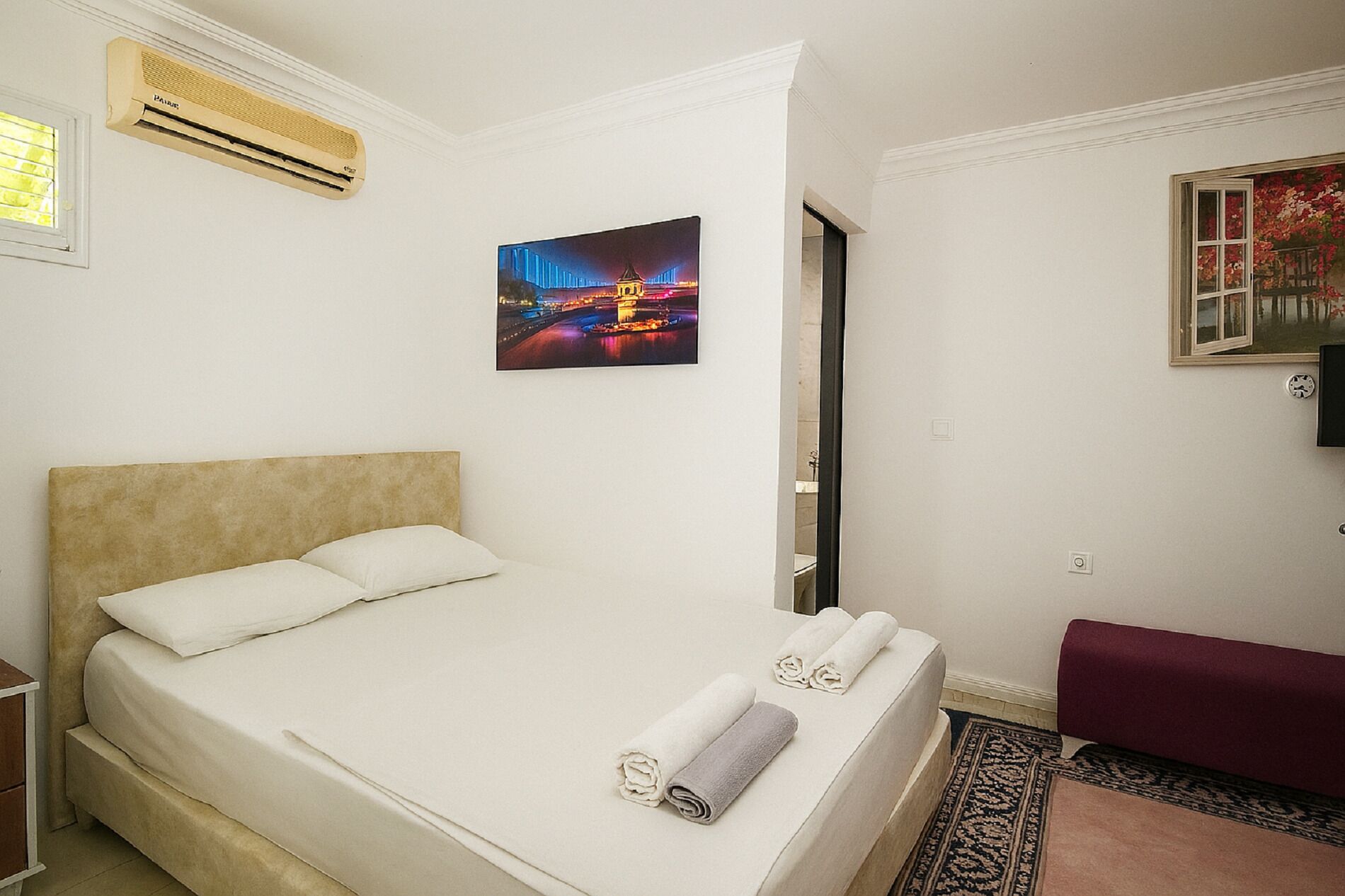 Ein Hotelzimmer mit Bett, einem Gemälde, einer Klimaanlage und einem Fenster.