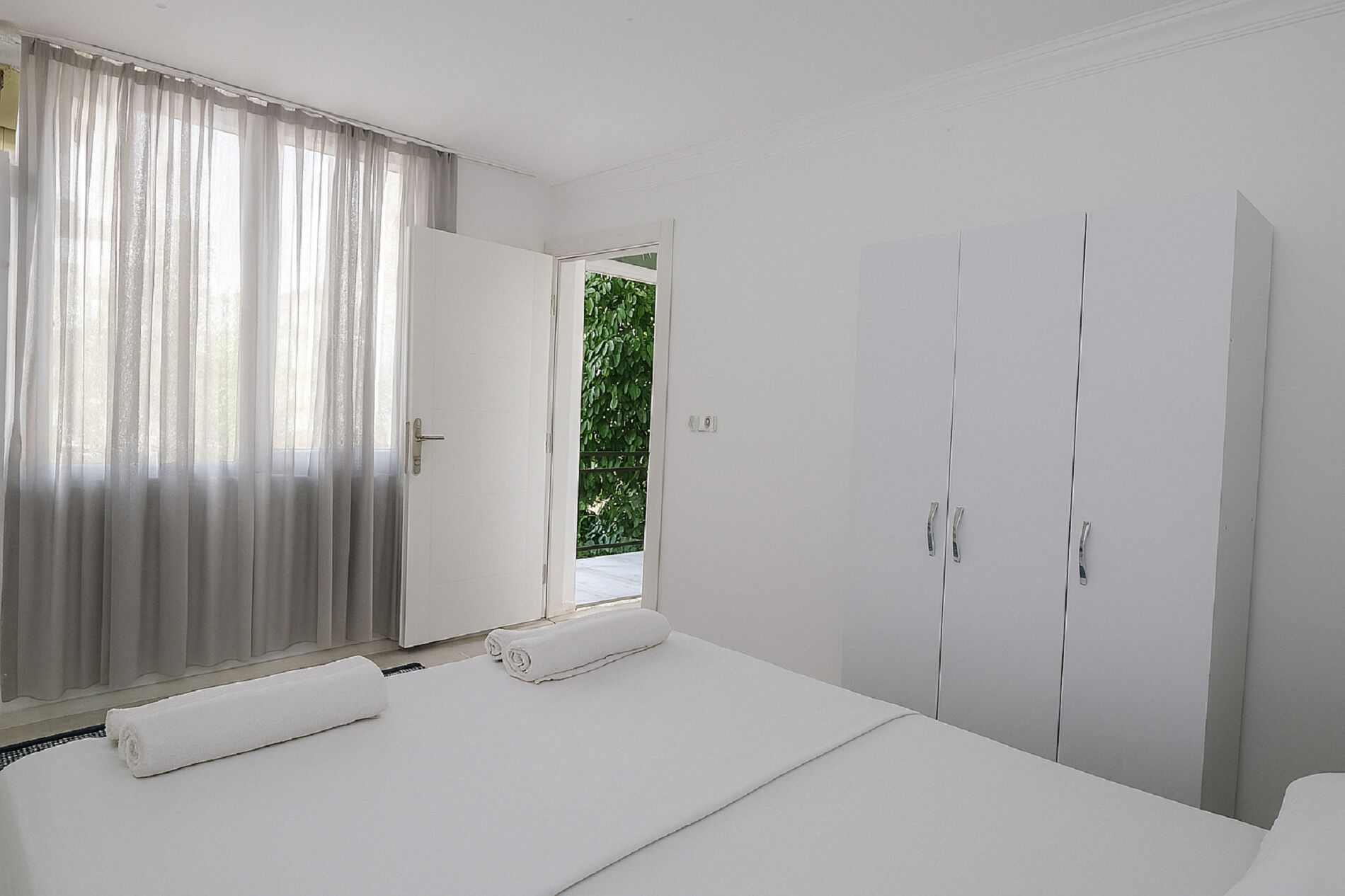 Ein Schlafzimmer mit einem Bett, einem Kleiderschrank und einem Fenster mit Vorhängen.
