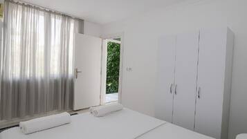 Ein Schlafzimmer mit einem Bett, einem Kleiderschrank und einem Fenster mit Vorhängen.