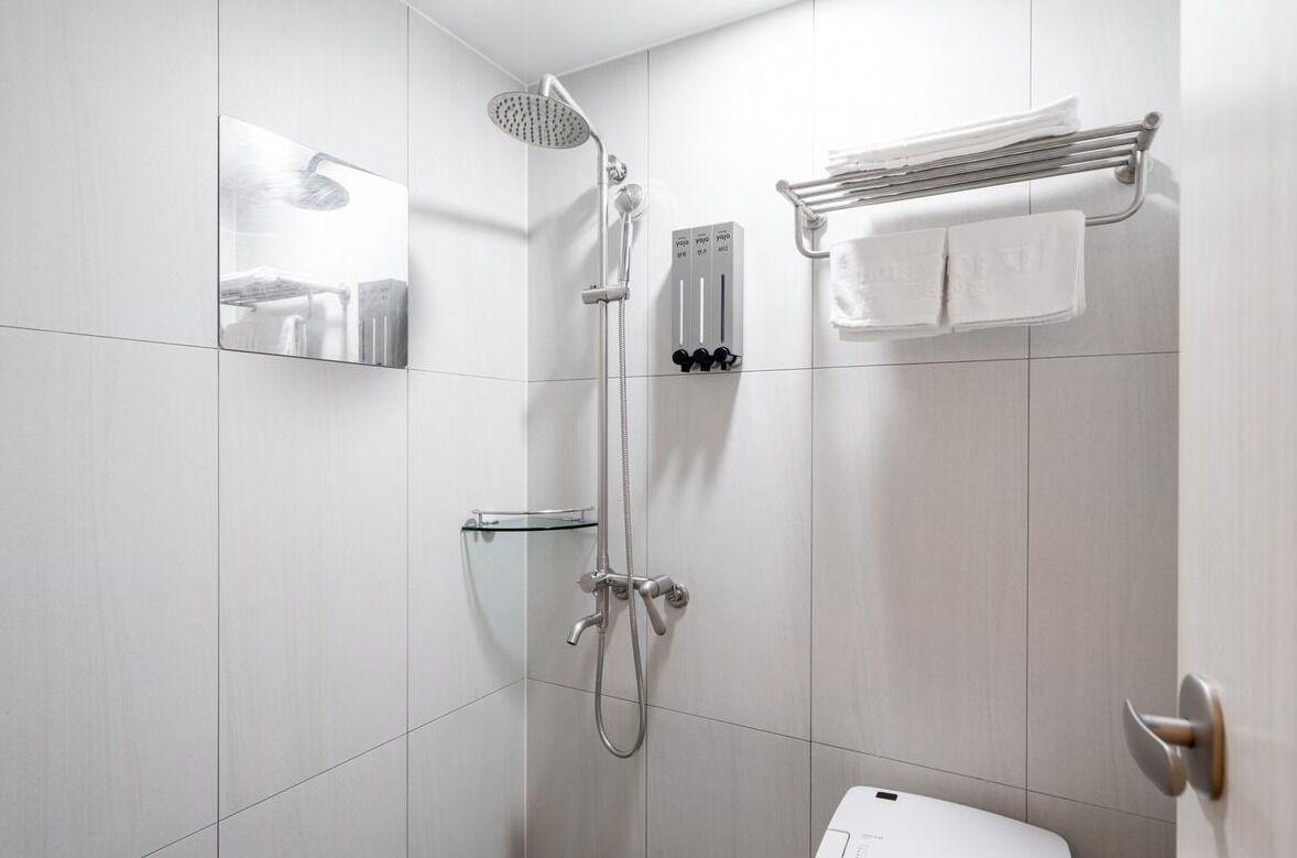 A modern bathroom with a shower, toilet, and a towel rack.