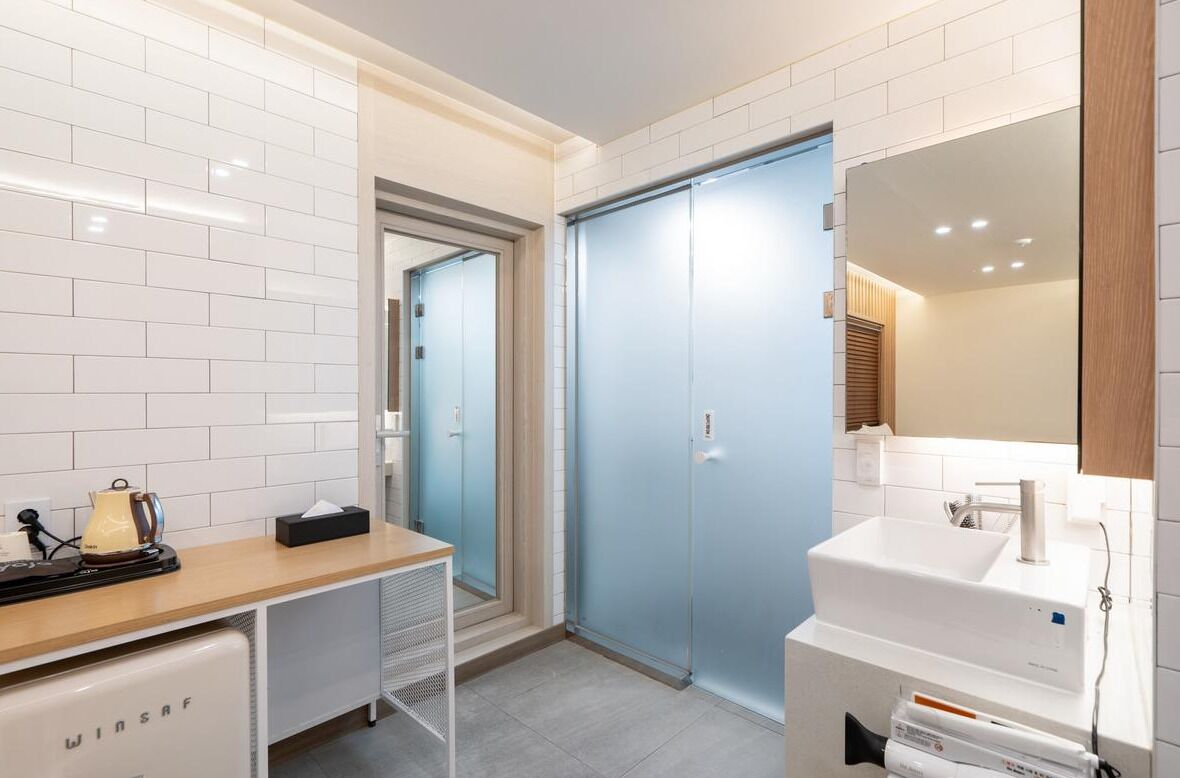 A modern bathroom with a white sink, a mirror, and a blue door.