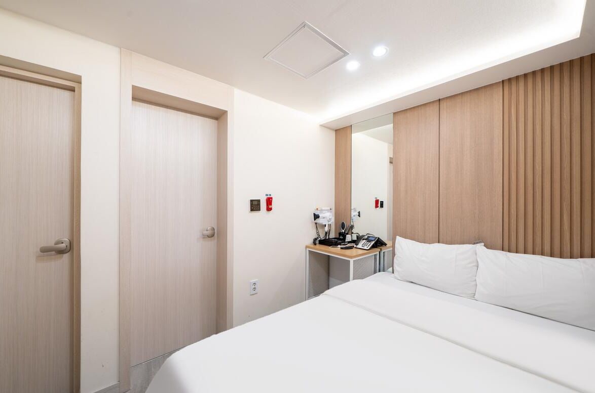Une chambre d’hôtel avec un lit, un bureau avec un téléphone et un miroir au mur.
