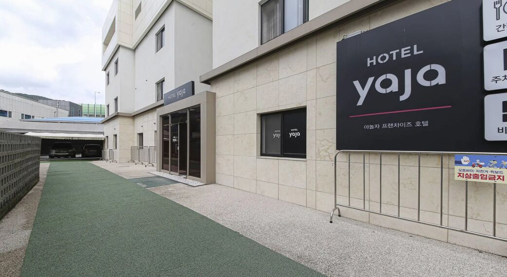 A hotel entrance with a sign for HOTEL YAJA, a covered parking area, and a pathway leading to the entrance.