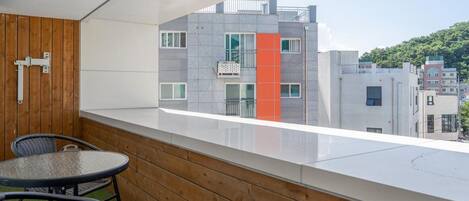 Un balcón con vistas a un edificio moderno, una pared de madera y una pequeña mesa con sillas.