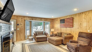 A living room with a fireplace, a large American flag, and a view through the glass doors.