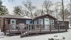 Eine Holzhütte mit Veranda, überdachter Terrasse und verschneitem Gelände.
