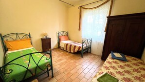 A bedroom with two beds, a nightstand, and a wooden wardrobe. - Apartment in Umbria Near Montefalco Winery (Giano dell'Umbria)