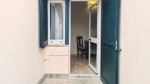 A narrow hallway with a door leading to a room with a tiled floor and a chair. - Apartment in Umbria Near Montefalco Winery (Giano dell'Umbria)