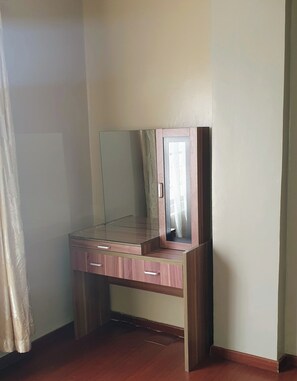 A corner room with a wooden desk, a mirror, and a curtain. - Luxurious 2 Bedroom in Kilimani With Scenic Views and Modern Amenities (Nairobi)