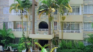 Um hotel com vários andares, varandas, piscina e paisagismo tropical.