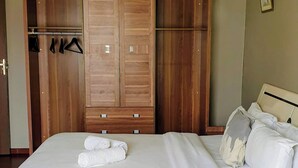 Een slaapkamer met een bed, een houten garderobe en een nachtkastje.
