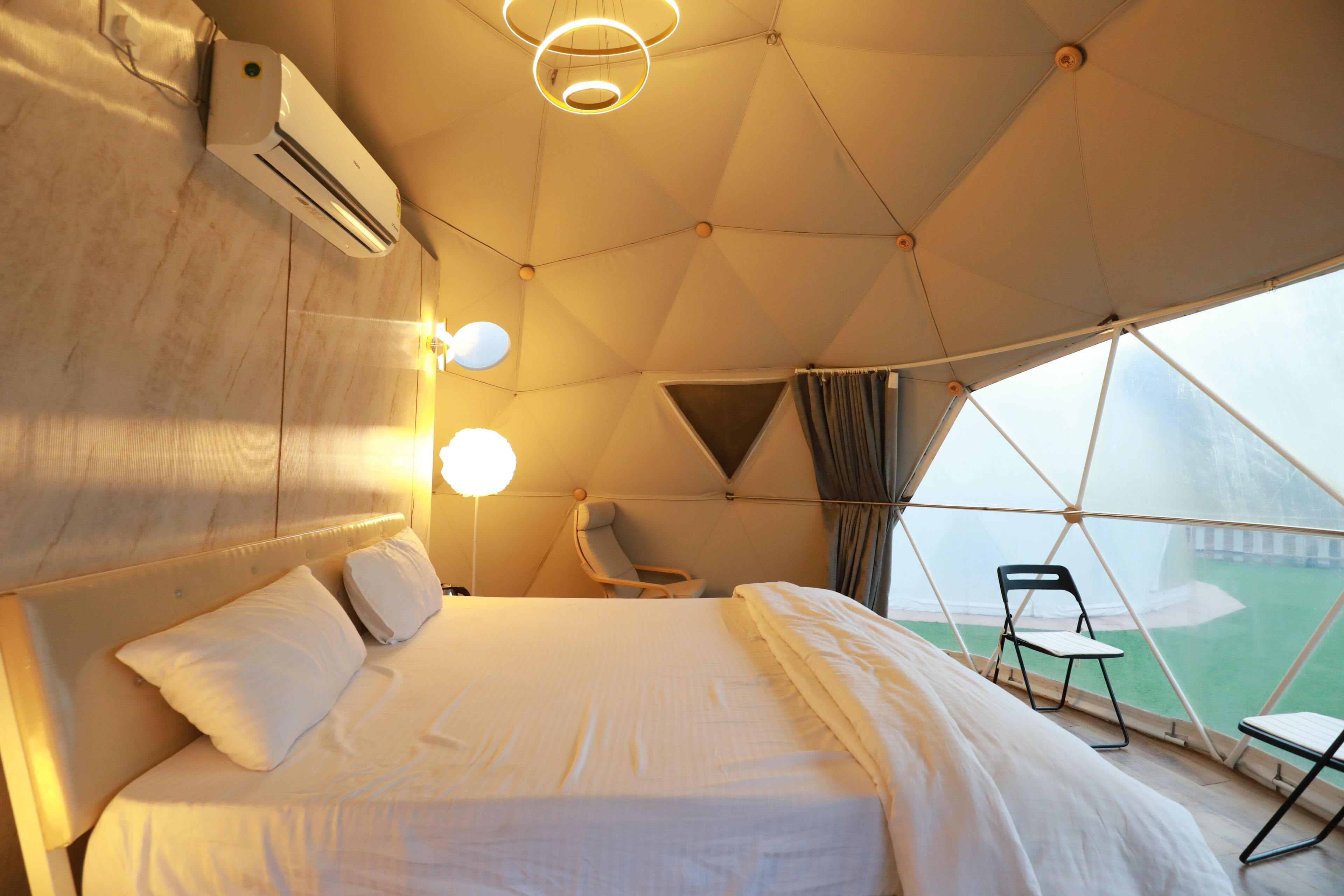 Una camera a tenda con un letto, una sedia e vista sulla natura.