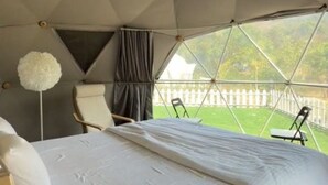 A tent-style room with a bed, a chair, and a view of the outdoors. - Harmony Hills (Paud)