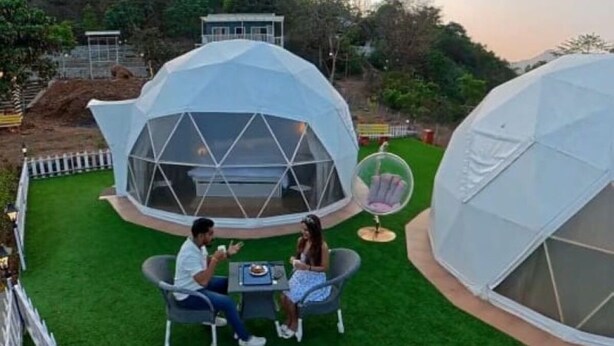 Two geodesic dome structures with a grassy lawn, a dining table, and chairs. - Harmony Hills (Paud)