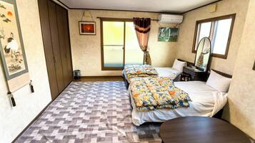 Un dormitorio con suelo a cuadros, una cama con ropa de cama estampada, una pequeña mesa redonda y una ventana con cortinas.