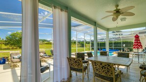 Eine überdachte Terrasse mit Pool, Gartenmöbeln und Blick auf die umliegende Landschaft.