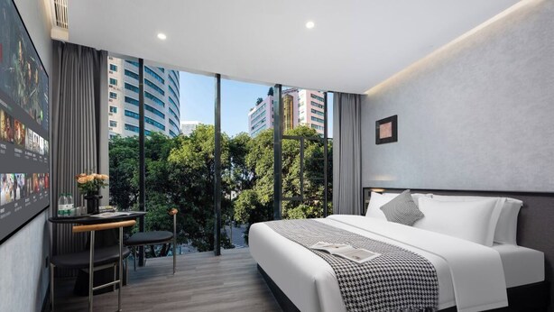 Una habitación de hotel moderna con una cama grande, un escritorio y vista a la ciudad.
