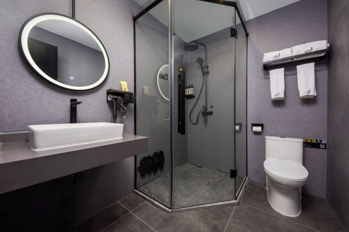 Un baño moderno con ducha de vidrio, un lavamanos blanco y un inodoro.