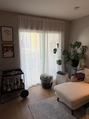 A living room with a sofa, a coffee table, a plant, a radiator, and a wall-mounted shelf with bottles. - Perfect 2-bedroom apartment in charming residential area in mid city Los Angeles (Los Angeles)
