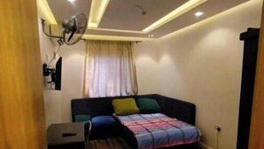 Een kleine kamer met een bed, bureau en plafondventilator.