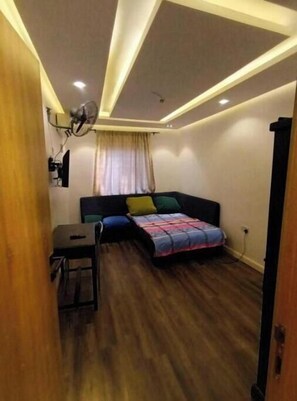 Ein kleines Zimmer mit einem Bett, einem Schreibtisch und einem Deckenventilator.